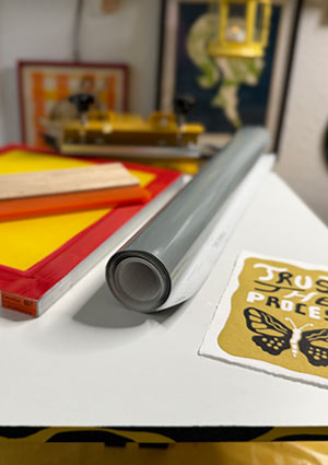 image showing screen, rolled vinyl foil and final print next to each other