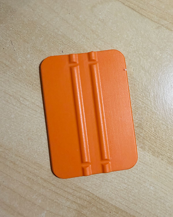 Orange plastic squeegee on a light wood table